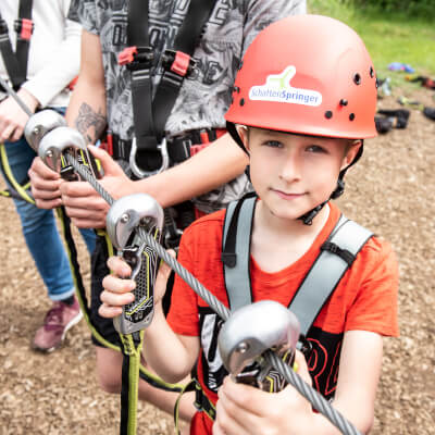 Kind steht an gesichert an einem Sicherungsseil und schaut in die Kamera